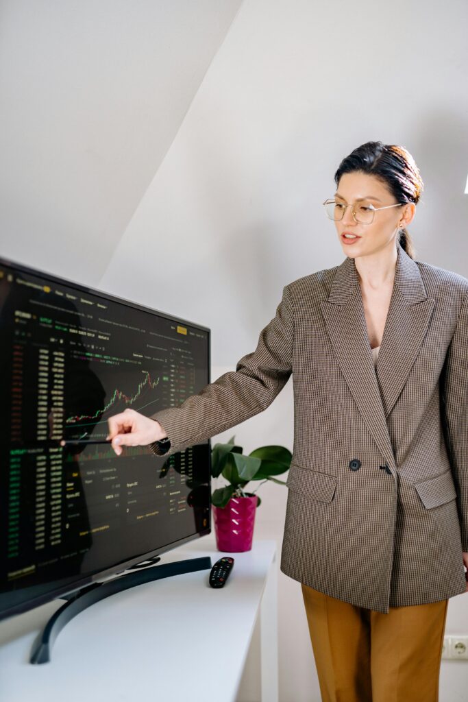 A professional woman in an office analyzing cryptocurrency charts on a monitor.